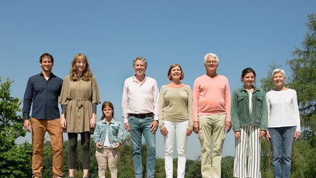 Menschen verschiedenen Alters, mit und ohne Behinderung, stehen lächelnd nebeneinander.