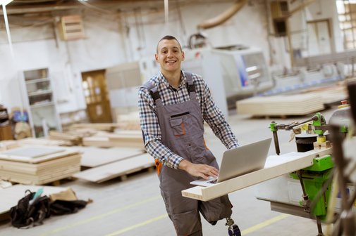 Ein junger Mann mit einer Beinprothese an seinem Arbeitsplatz in einer M&ouml;belfabrik.