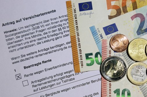 Ein Antrag auf Erwerbsminderungsrente. Darauf liegen Euro-Scheine und -Münzen.