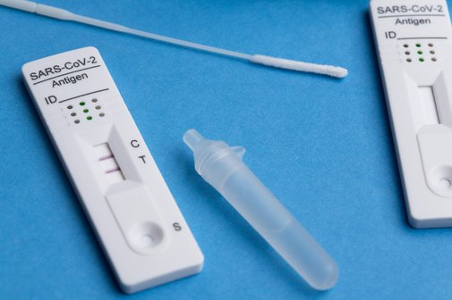 Ein positiver Corona-Test auf einer blauen Unterlage.