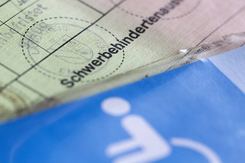 Ein Schwerbehindertenausweis im alten Format. Darauf ist ein Parkausweis f&uuml;r schwerbehinderte Menschen mit dem blauen Rollstuhl-Piktogramm zu erkennen.