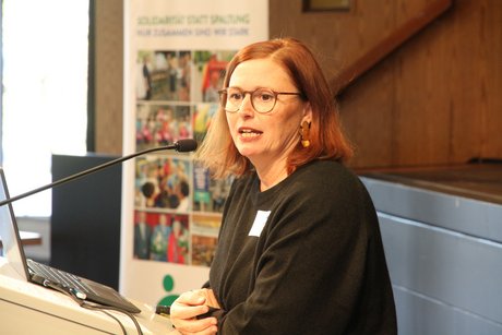 Referentin Kathrin Weinkauf Frau mit halblangem roten Haar und schwarzer Brille beim engagierten Vortrag.