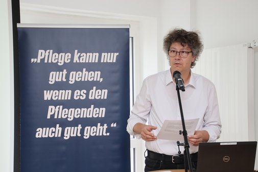 Mann im weißen Hemd liest seine Vision der Pflege des Jahres 2035 von einem Blatt ab. 