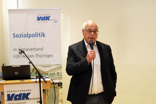 Ein Mann steht vor einer Wand und einem Roll-up des Sozialverband VdK Hessen-Th&uuml;ringen und spricht in ein Mikrofon.