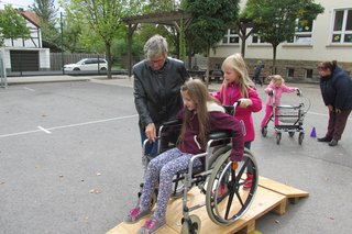 Eine Frau und zwei Kinder, eines davon sitzt im Rollstuhl