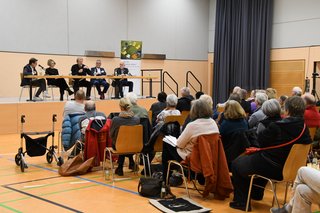 Blick von hinten auf Publikum und Podium 