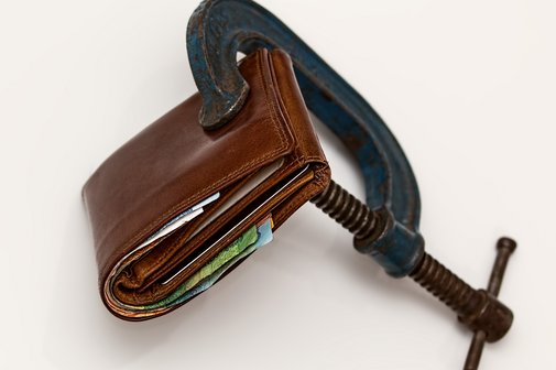 Eine Geldb&ouml;rse zusammengepresst in einem Schraubstock