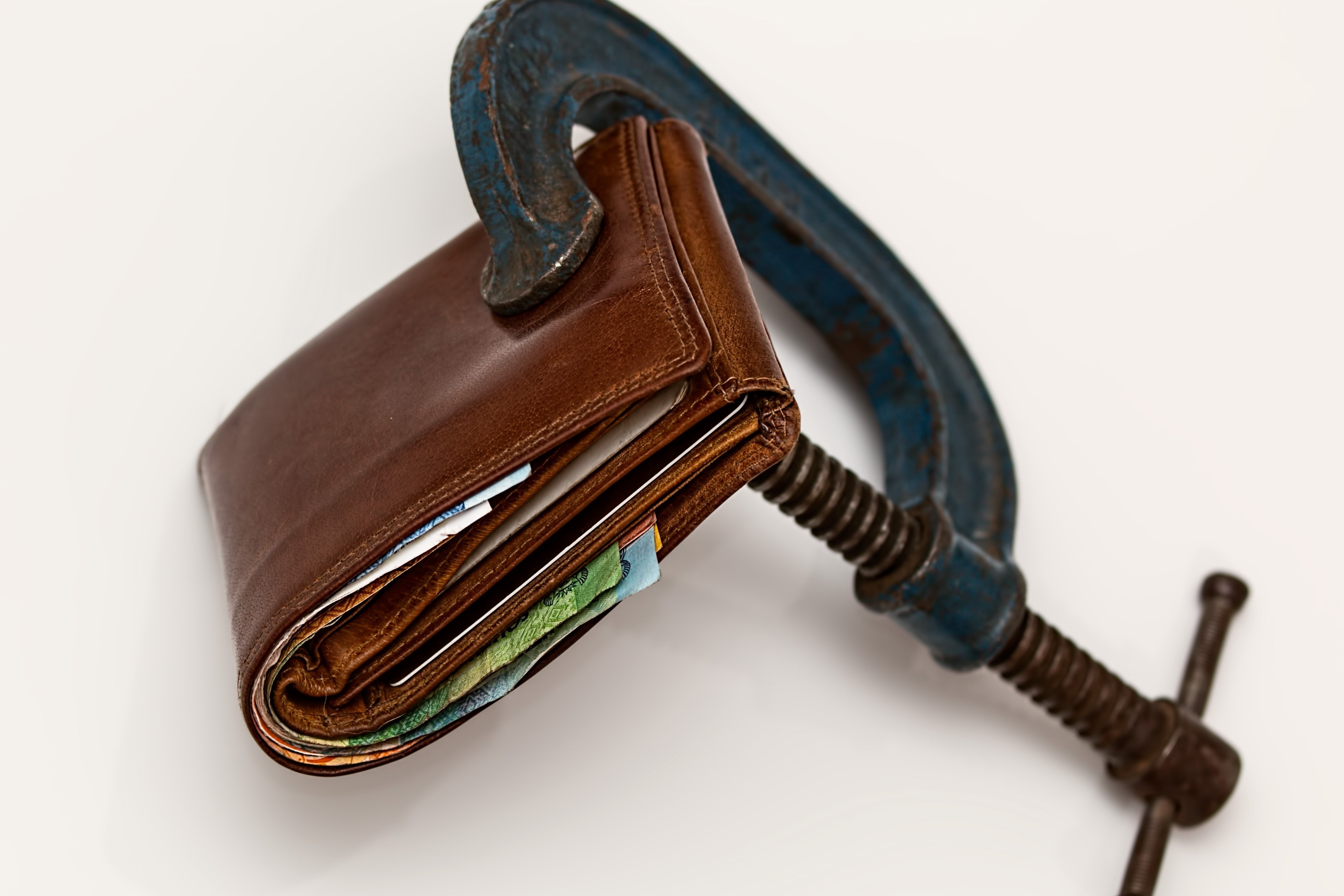 Eine Geldbörse zusammengepresst in einem Schraubstock