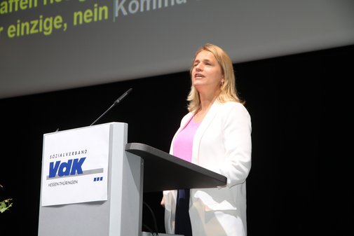 Frau in rosa Shirt und weißem Blazer am VdK-Rednerpult. 