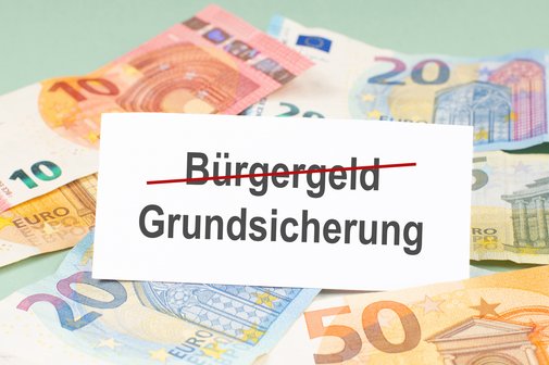10-, 20- und 50-Euro-Geldscheine vor hellgr&uuml;nem Hintergrund mit wei&szlig;er Fl&auml;che, auf der die W&ouml;rter B&uuml;rgergeld und Grundsicherung stehen
