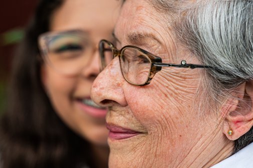 Zwei fr&ouml;hliche Gesichter: das einer &auml;lteren Frau im Profil und im Vordergrund, und dahinter ein lachendes M&auml;dchen. 