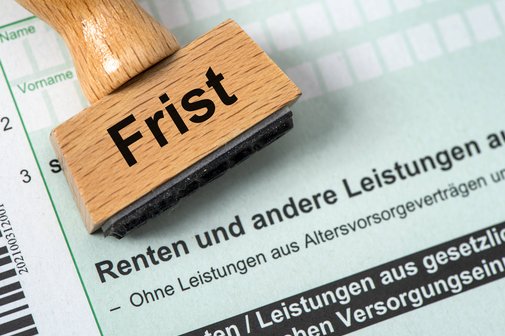 Formular für Einkommensteuer wg. Einkünfte durch Renten. Ein Holzstempel mit Aufdruck "Frist" liegt auf einem Formular der Einkommensteuererklärung zu Renteneinkünften.