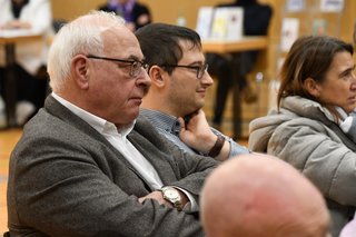 Ein junger und ein älterer Mann sitzen nebeneinander und hören beide sehr konzentriert bei der Diskussion zu.