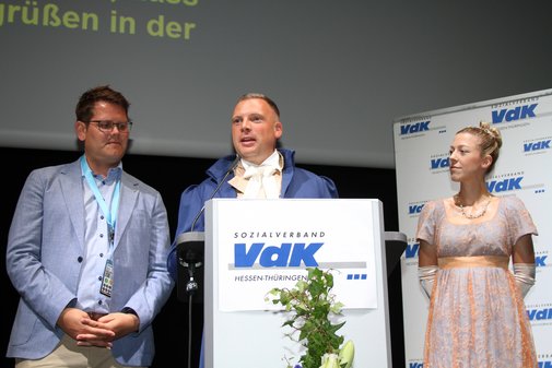 Ein Prinz mit blauem Frack und weißem Jambom in der Mitte, flankiert von der Hessentagsprinzessin im rosa Kleid und Hochsteckfrisur und einem Herrn im hellen sommerlichen Anzug. ermeister von 