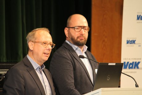 Die Bauherren des Krefelder Wohnprojekts Ein großer und ein kleiner Mann stehen nebeneinander am Rednerpult.