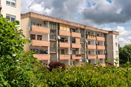 Ein vierst&ouml;ckiger Wohnblock mit Balkonen im Gr&uuml;nen 