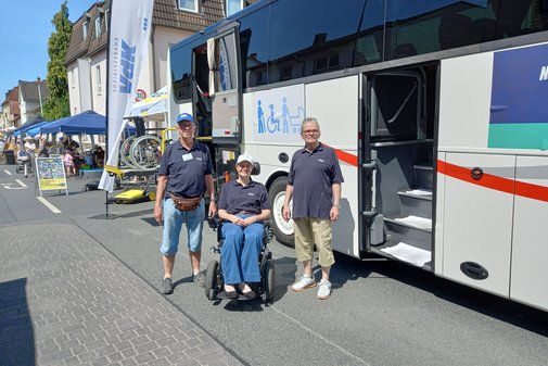 Drei Menschen vor einem Reisebus