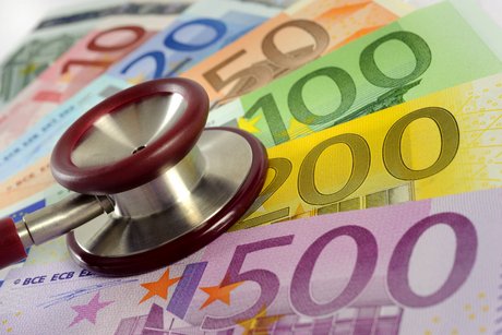 Ein Stethoskop liegt auf einem Fächer mit Euro-Geldscheinen. 