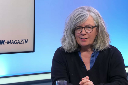 Frau mit grauem Haar und Brille im Studio bei der Aufzeichnung des Interviews. 
