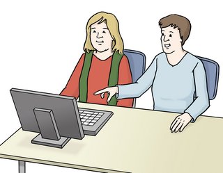 Zwei Frauen sitzen vor einem Computer. Eine Frau zeigt der anderen etwas auf dem Bildschirm.
