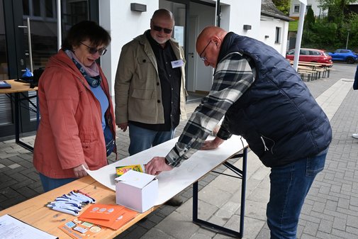 Drei Menschen an einem Informationsstand