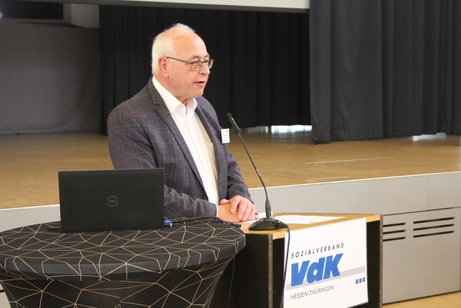Eine Mann steht an einem Pult und h&auml;lt eine Rede