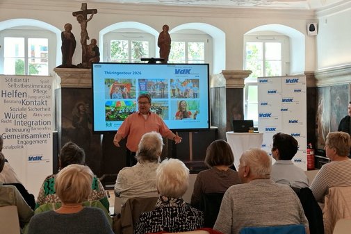Ein Mann hält vor mehreren Menschen einen Vortrag