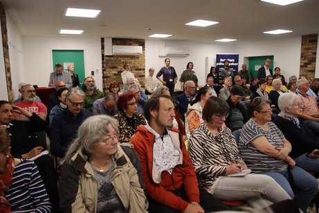 Blich in den Saal. Alle Stühle sind besetzt, im Hintergrund stehen mehrere Leute, die keinen Stuhl mehr abbekommen haben. 