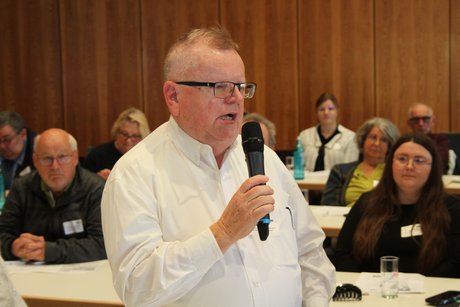 Karl Sellent Zuhörer aus dem Publikum ist aufgestanden und spricht seine Frage in ein Mikrofon.