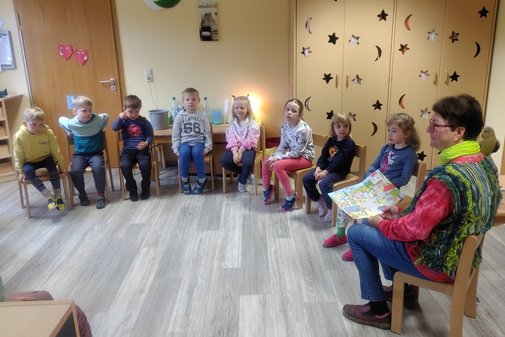 Kinder sitzen im Stuhlkreis und verfolgen aufmerksam die Geschichte von Käpt'n Kork, die ihnen von einer vdK-Ehrenamtlichen vorgelesen wird. 