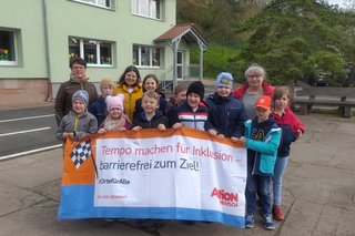 Kindergruppe steht zusammen hinter einem Transparent, das mehr Tempo bei der Verwirklichung von Inklusion fordert.