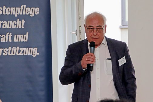 VdK-Landesvorsitzender Weimann begrüßt stehend die Gäste der Veranstaltung 