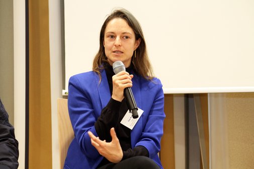 Frau sitzt auf einem Stuhl und spricht in ein Mikrofon