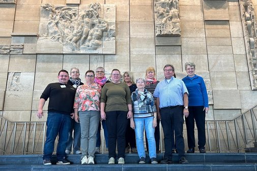 Mehrere Menschen vor einer Wand mit Reliefs