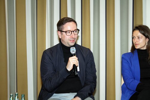 Mann sitzt und h&auml;lt ein Mikrofon in der Hand