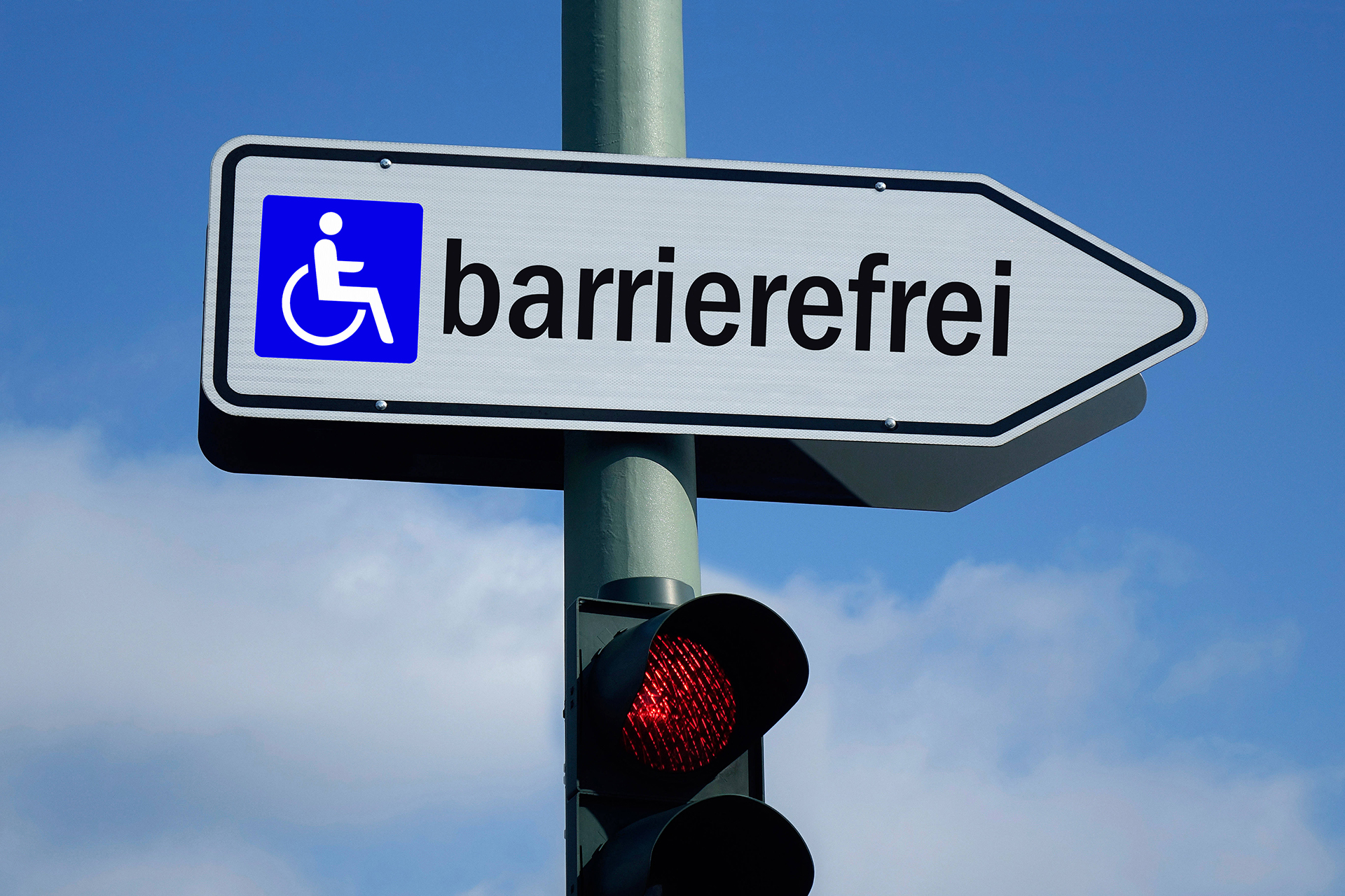 Auf dem Bild sieht man ein Verkehrsschild, das die Richtung anzeigt. Es zeigt in Richtung "Barrierefrei"