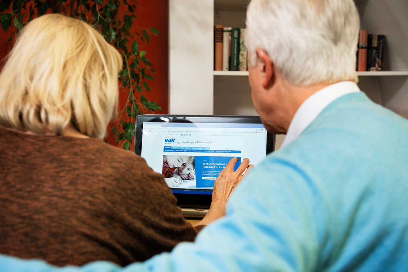Ein &auml;lteres Paar am Computer, auf dem Bildschirm sieht man die Facebook-Seite des VdK Deutschland