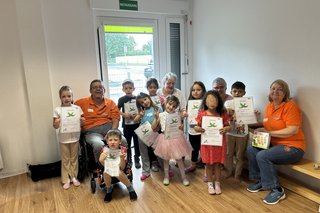 Das Bild zeigt die teilnehmende Kindergruppe, die zum Abschuss des Sensibilisierungs Parcours eine Teilnehmerurkunde, über die sie sich sehr freuten.