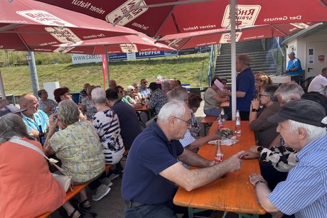 Personen auf Bierzeltgarnituren in Gespr&auml;chen