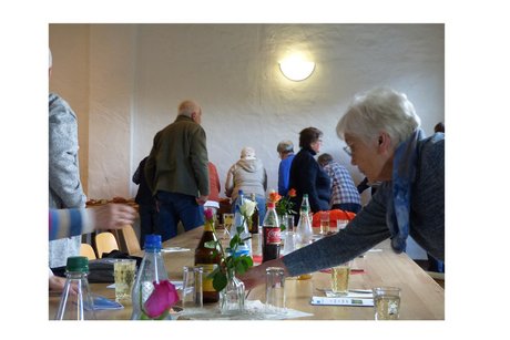 mehrere personen sitzen an tischen, andere stehen am buffet an