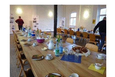 2 tischreihen die mit kaffeegeschirr, wasser, kaffee, etageren mit wurst, gem&uuml;se und k&auml;se eingedeckt sind