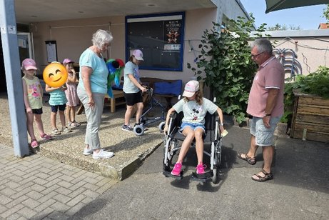 die 2 Betreuer S. Ewe und H. Reichmann und die Kindern &uuml;ben den Umgang mit Hilfsmittel wie Rollator und Rollstuhl