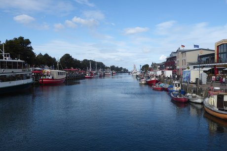 Blick auf den Hafen Warnemünde, am Ufer sind auf beiden Seiten Gebäude zu sehen