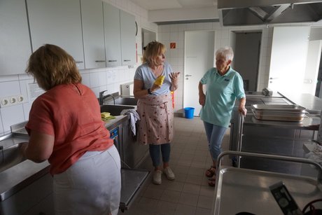 Arbeitsbereite Mitglieder bereiten sich auf das Spülen der Teller und Gläser vor.