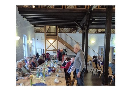 an einem tisch sitzen personen die sich l&auml;chelnd unterhalten