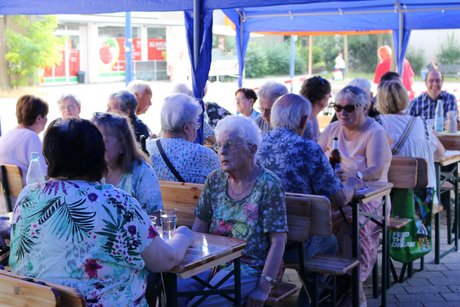 Besucher des Grillfests sitzen an Tischen und lassen sich das Essen schmecken