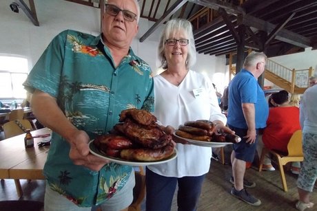 2 personen halten je einen teller vollbeladen mit wurst und steaks