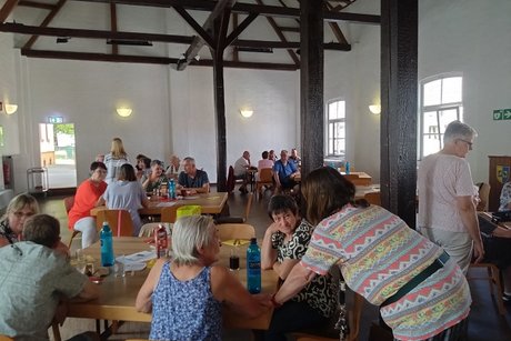 mehrere personen sitzen an tischen und unterhalten sich