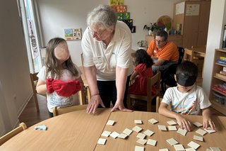 Das Bild zeigt Kinder bei der Hör und Fühlstation, Hannelore Trabandt erklärt die Regeln.