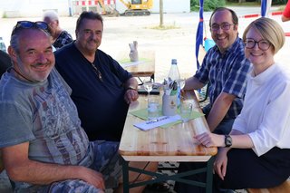 Sozialdezernentin Dr. Patricia Becher sitzt mit Vertretern des VdK, von Ideen für Biebrich und des Weissen Rings beim Grillnachmittag an einem Tisch.